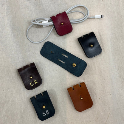 set of leather cable holders with personalised gold and silver lettering 
